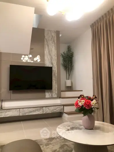 Elegant living room with modern decor, featuring a flat-screen TV, stylish lighting, and a chic marble coffee table.