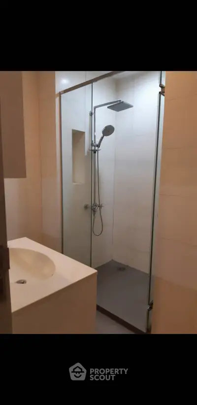 Modern bathroom with glass shower enclosure and sleek sink design.