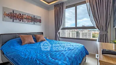Cozy bedroom with city view, featuring a blue bedspread and modern decor, perfect for urban living.