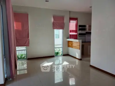 Spacious living room with natural light and modern design, featuring large windows and sleek flooring.