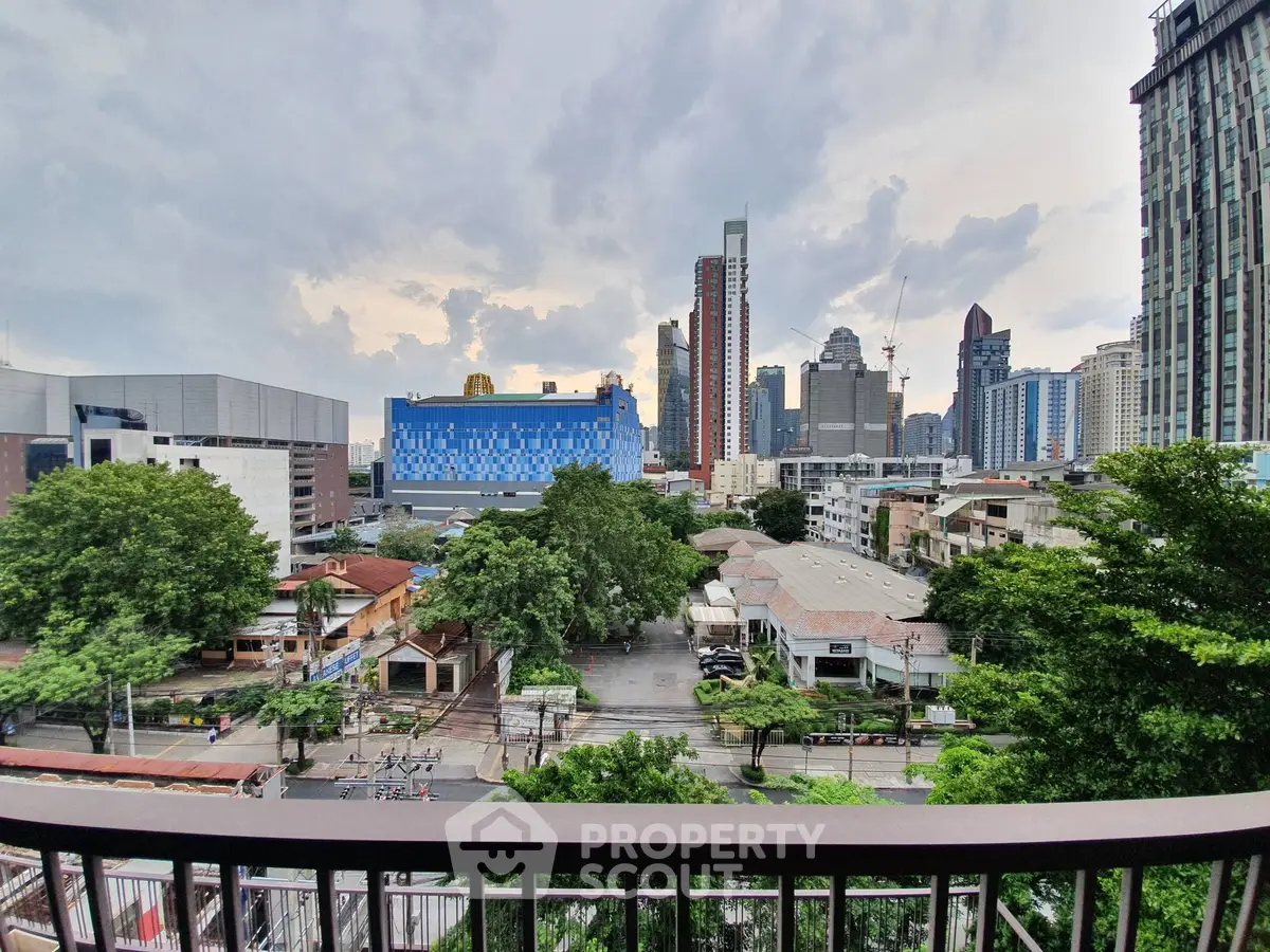 Stunning cityscape view from a high-rise balcony overlooking urban skyline and lush greenery.