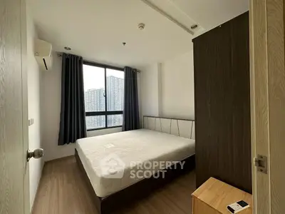 Modern bedroom with large window and city view in a stylish apartment.