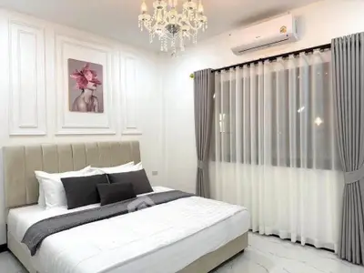 Elegant bedroom with chandelier, large bed, and stylish decor, perfect for a cozy retreat.