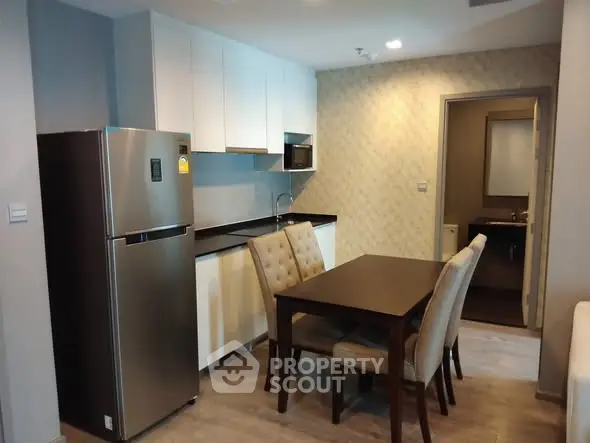 Modern kitchen with dining area featuring stainless steel fridge and elegant dining set.