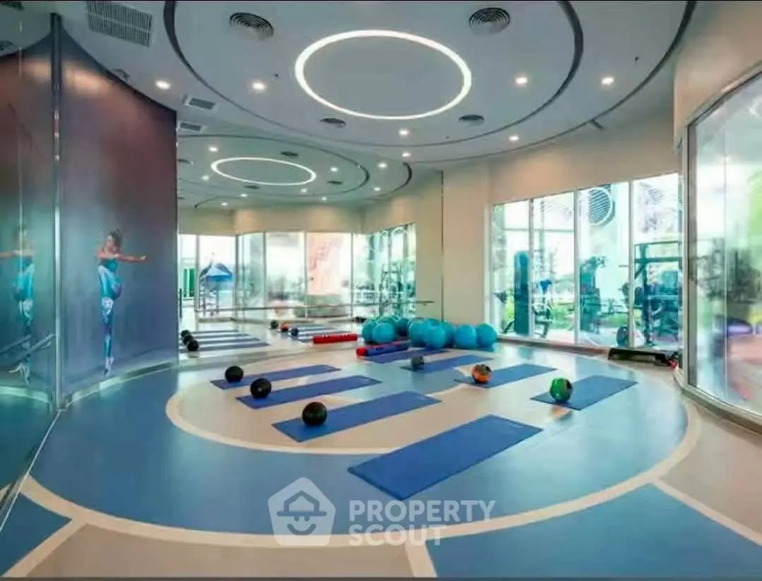 Modern gym with yoga mats and exercise equipment in a luxurious building.