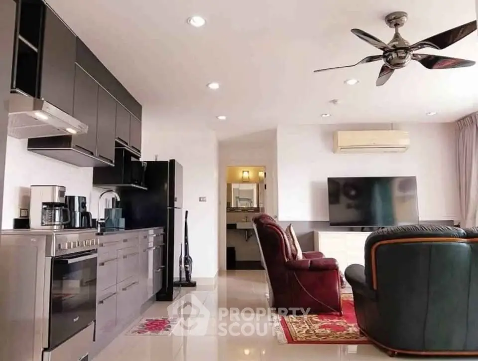 Modern open-layout living room with sleek kitchen, cozy seating, and ceiling fan, perfect for entertaining.