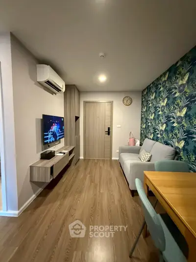 Modern living room with stylish decor and wooden flooring, featuring a cozy sofa and wall-mounted TV.
