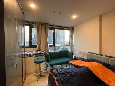 Modern bedroom with city view, cozy seating, and stylish decor in urban apartment.