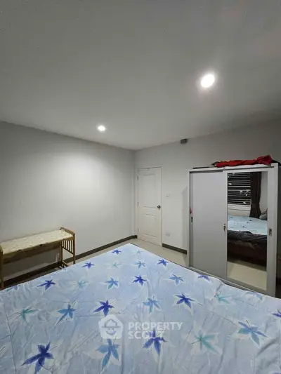 Cozy bedroom with floral bedding and mirrored wardrobe, perfect for relaxation and comfort.