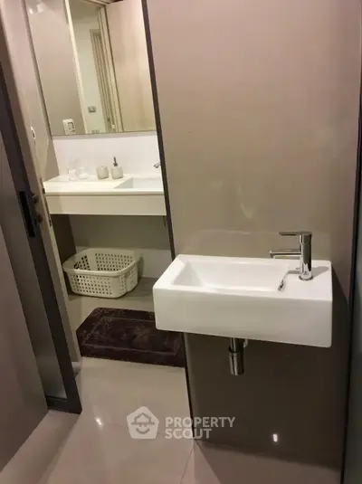 Modern bathroom with sleek fixtures and minimalist design, featuring a compact sink and stylish decor.
