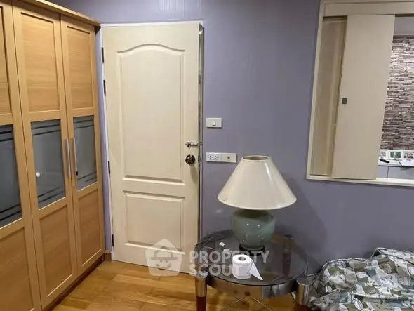 Cozy bedroom with wooden wardrobe and stylish lamp on glass table