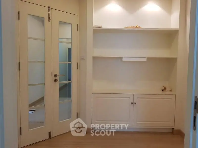 Elegant interior with built-in shelving and double glass doors, perfect for modern living spaces.