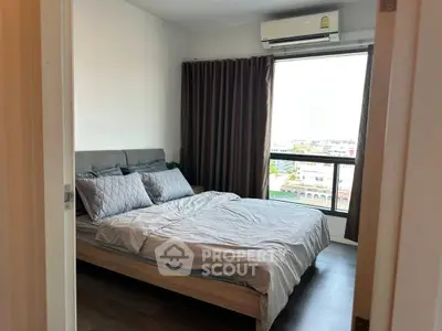 Modern bedroom with large window and air conditioning, featuring stylish decor and natural light.