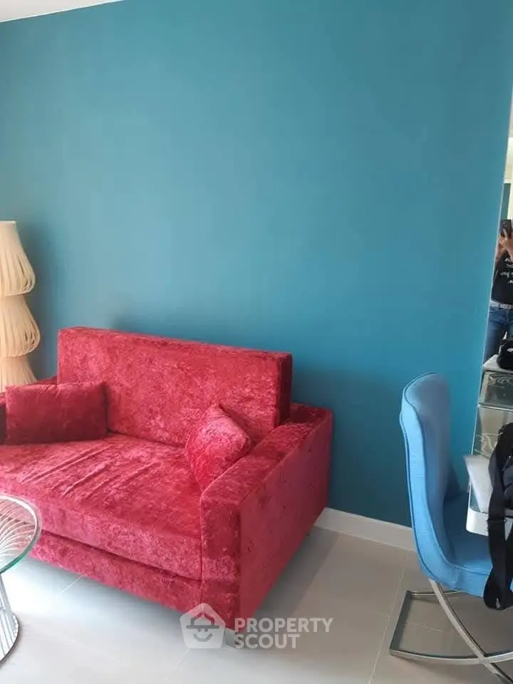 Stylish living room with vibrant red sofa and modern blue accent wall.
