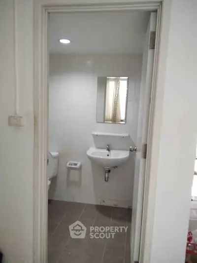 Compact bathroom with sink, mirror, and toilet in a modern apartment.