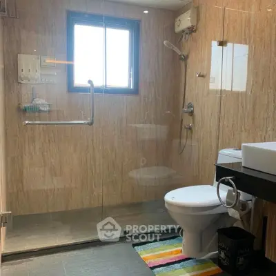 Modern bathroom with glass shower, sleek fixtures, and natural light.