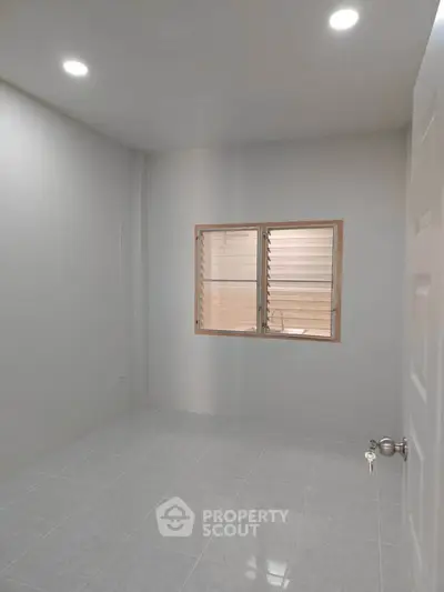 Minimalist empty room with tiled floor and window, ideal for customization.