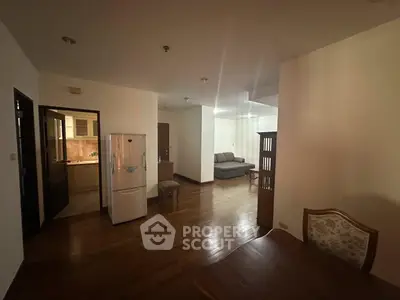Spacious living area with wooden flooring and modern furniture in a cozy apartment.