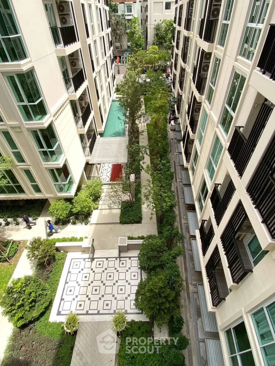 Stunning aerial view of modern apartment complex with lush garden and pool area.
