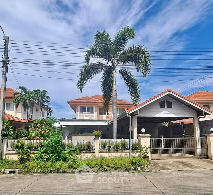 Charming suburban house with red-tiled roof and lush garden under a clear blue sky.