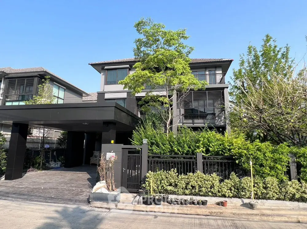Modern two-story house with sleek design and lush greenery in a suburban neighborhood.
