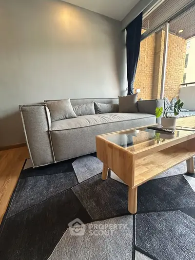 Modern living room with stylish gray sofa and wooden coffee table, featuring a cozy rug and natural light.