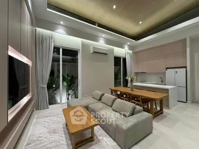 Modern open-plan living room with sleek kitchen, stylish furniture, and ambient lighting.