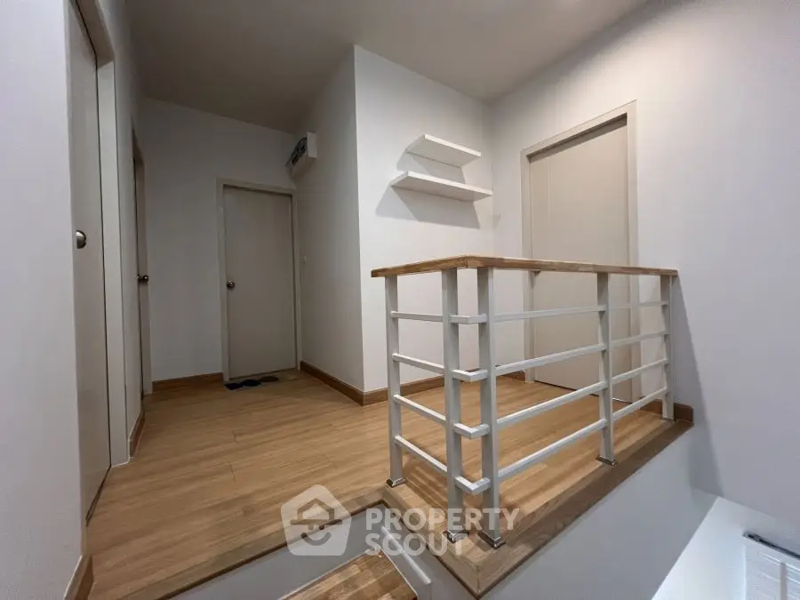 Modern interior hallway with wooden flooring and sleek railing design