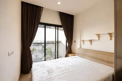Spacious bedroom with large window and balcony access, featuring modern design and natural light.