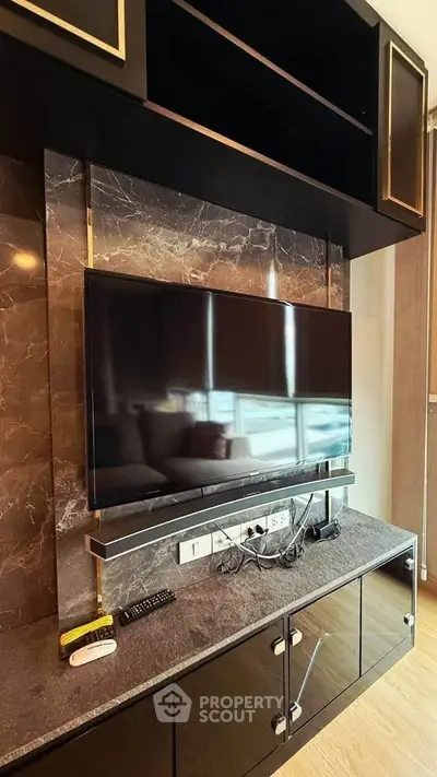 Modern living room with sleek TV setup and marble accents, perfect for entertainment.