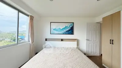 Bright bedroom with large window and ocean wave artwork, modern and inviting.