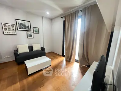 Modern living room with hardwood floors, cozy sofa, and large window with curtains.
