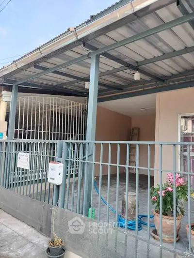 Charming covered patio with metal railing and potted plants, perfect for outdoor relaxation.