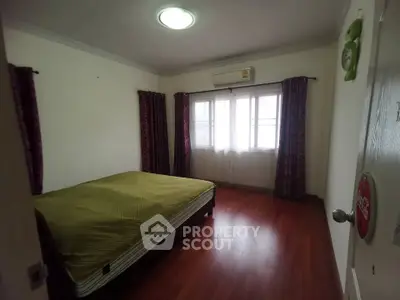 Spacious bedroom with wooden flooring and natural light