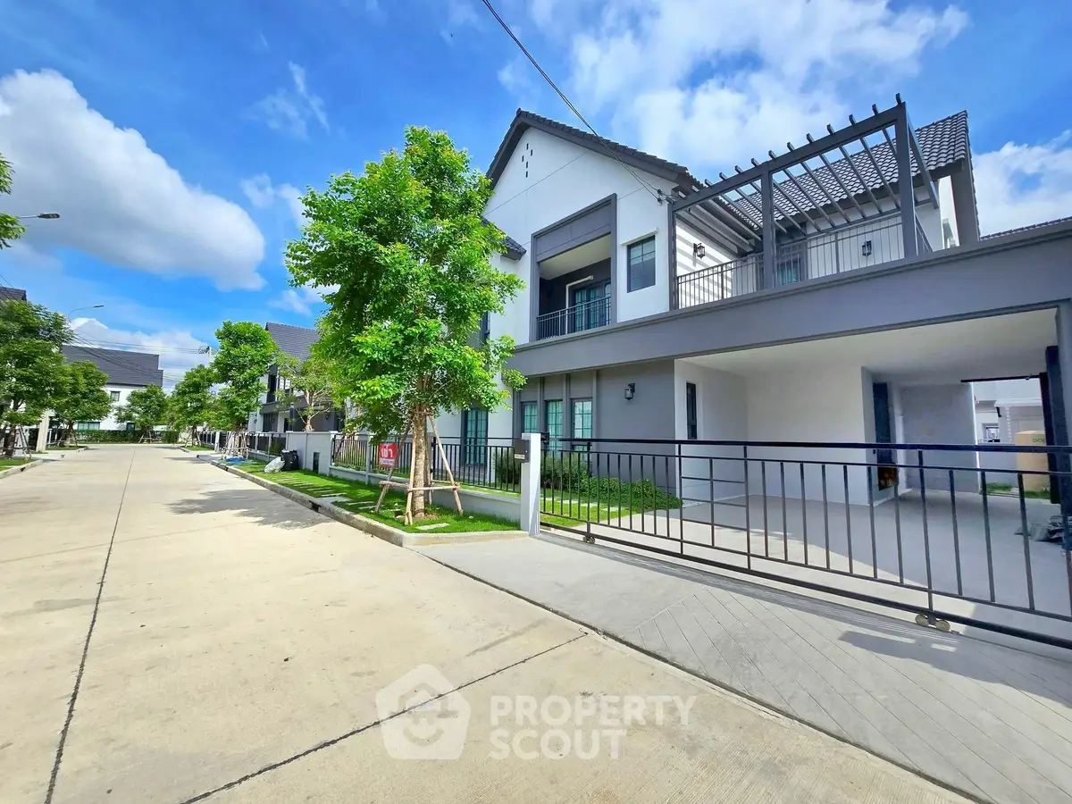 Modern two-story house with spacious driveway and lush greenery in a serene neighborhood.