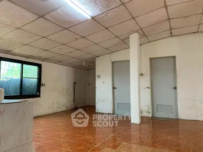 Spacious room with tiled floor and two doors, ideal for renovation.