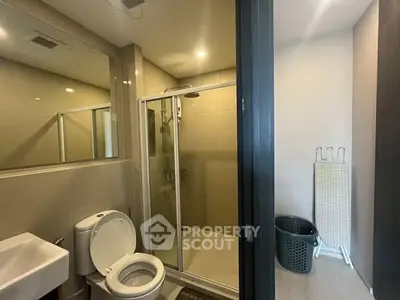 Modern bathroom with glass shower and sleek fixtures in contemporary apartment.