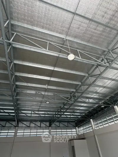 Spacious industrial-style interior with high metal ceiling and ample natural light.