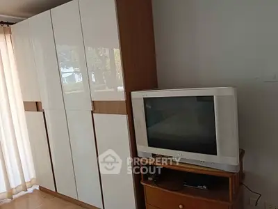Cozy bedroom with sleek wardrobe and vintage TV setup.