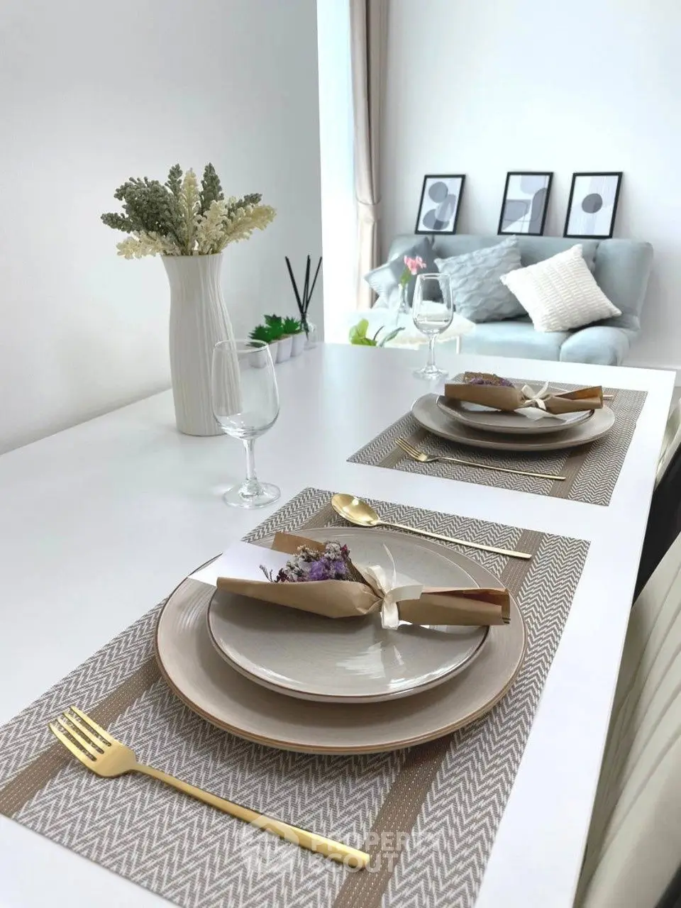 Elegant dining setup with modern decor and cozy living room in background.