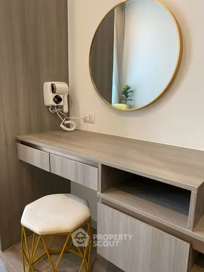 Modern bedroom vanity with round mirror and stylish stool in elegant interior design.
