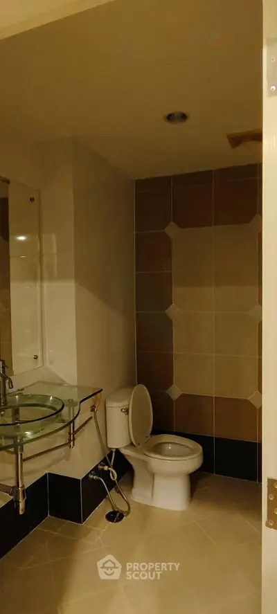 Modern bathroom with glass sink and tiled walls in a stylish home.