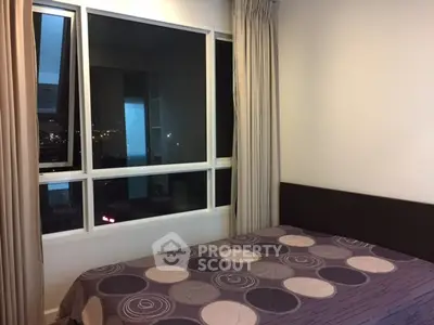 Cozy bedroom with large window offering city views, featuring modern decor and neutral tones.