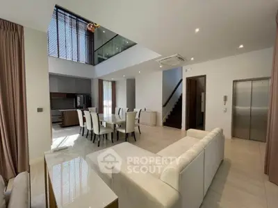 Luxurious open-plan living room with high ceilings and modern dining area in a stylish home.