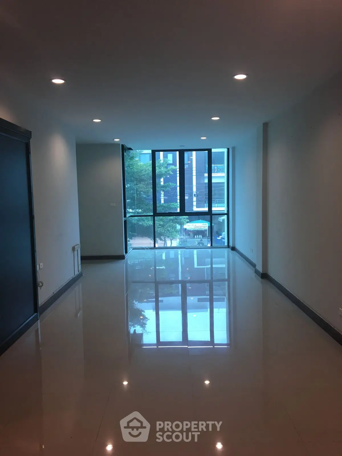 Spacious empty room with large windows and glossy tiled floor, ideal for customization.