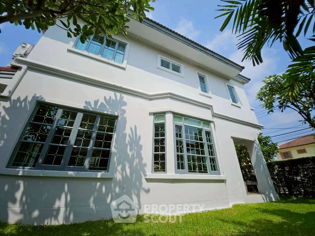 Charming two-story house with lush garden and large windows, perfect for family living.