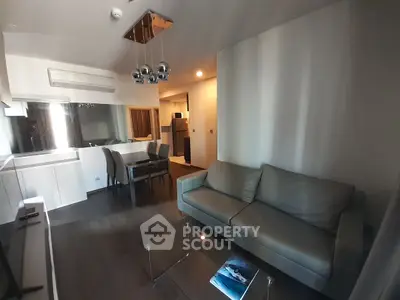 Modern living room with sleek furniture and dining area in open layout apartment.