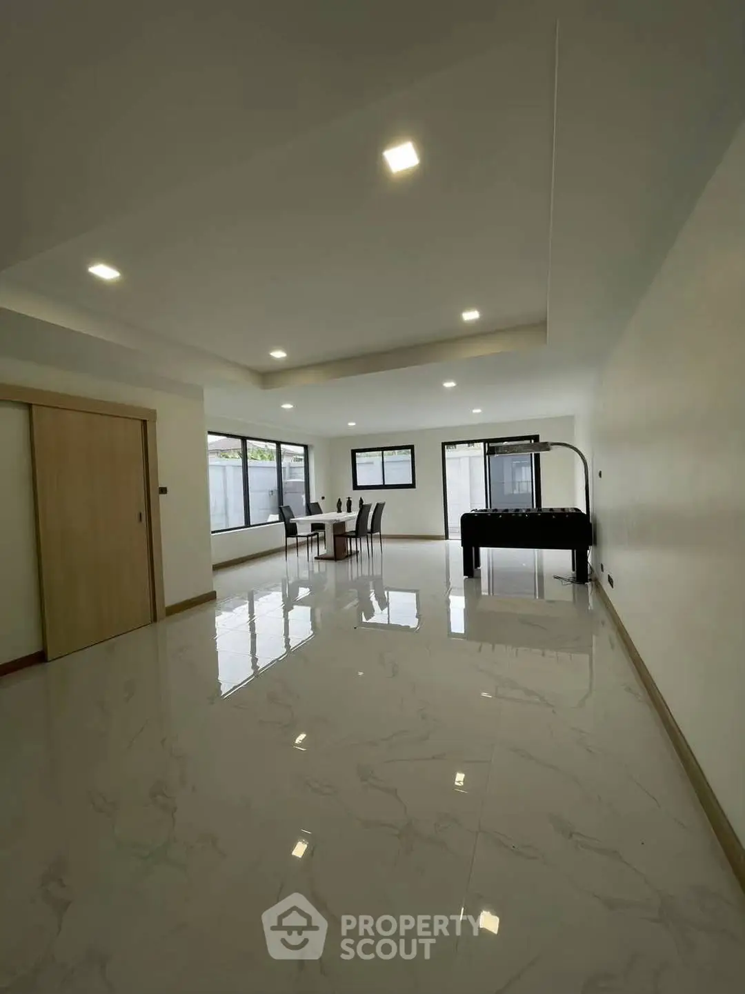 Spacious modern living room with glossy marble floors and large windows for natural light.