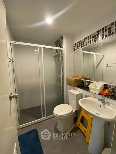 Modern bathroom with glass shower and sleek fixtures in contemporary apartment.