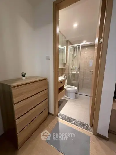 Modern bathroom with glass shower and wooden dresser in a cozy apartment